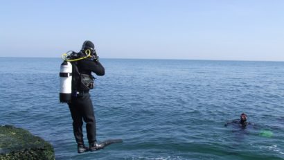 Scafandrii militari se luptă, cu valurile, ca să recupereze un cadavru pe plaja Modern
